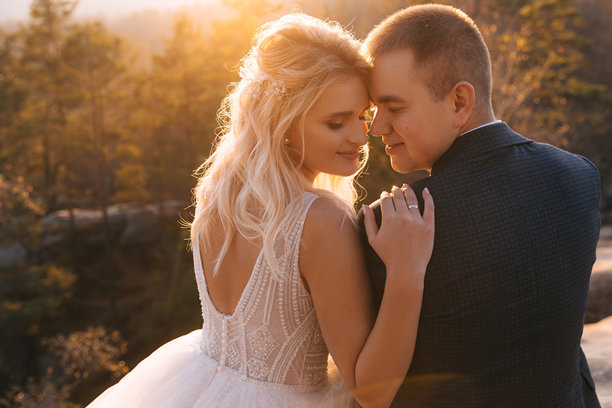 新郎新娘在日落时分温柔地相拥，背景是秋天的山脉，特写婚礼照片。图片下载
