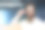 年轻男子戴着耳机坐在前台办公室的桌子旁，微笑着看向镜头，同时手里拿着眼镜，特写照片。图片下载