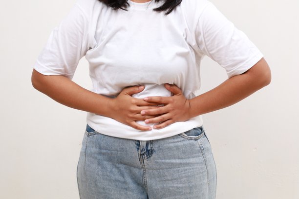 亚洲妇女胃痛的特写照片，弯腰和手放在肚子上，痛经不适图片下载