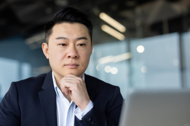 年轻亚洲男性商人在办公室专注地凝视着笔记本电脑屏幕的特写照片图片下载