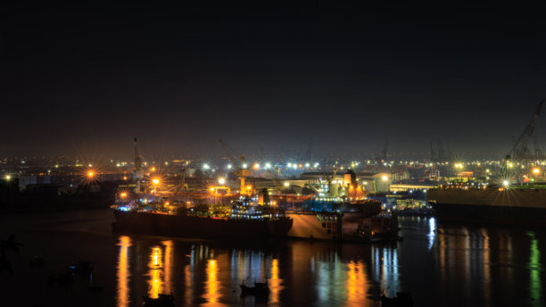 航拍视角的船厂干船坞维护与修理，集装箱船和油船在海上，夜间商业与工业服务的灯光照片，来自无人机。图片下载