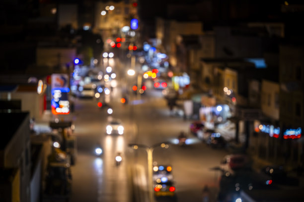 傍晚时分中央城市街道的照片，模糊的车灯和霓虹灯招牌。图片下载