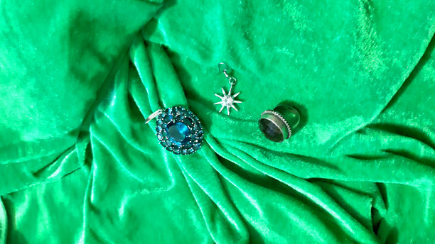 女性金色珠宝与蓝色宝石在明亮的绿色织物上。背景设计，摄影新颖。纺织品，面料模板，现代照片。图片下载