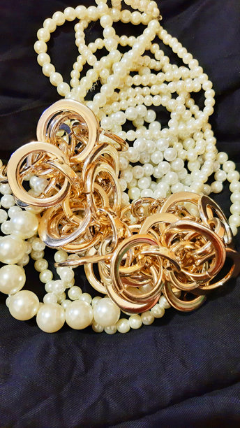 黑色织物上的珍珠女装珠宝和黄金。背景设计，摄影新颖。纺织品，面料模板，现代照片。图片下载