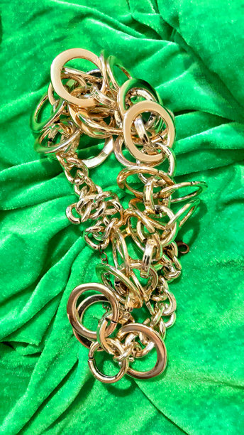 大型金链，装饰在明亮的绿色织物上。背景设计，摄影新颖。纺织品，面料模板，现代照片。图片下载
