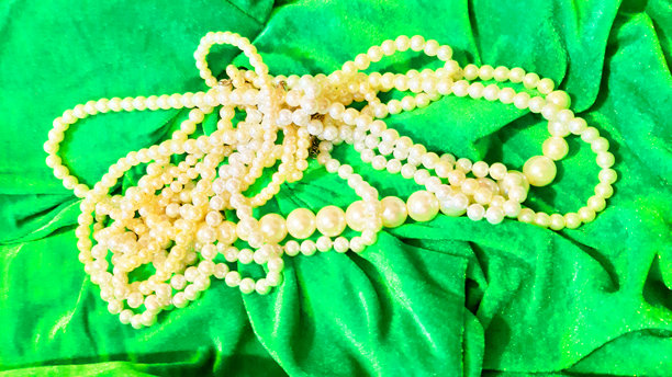 绿色表面上的珍珠女性珠宝。背景设计，摄影新颖。纺织品，面料模板，现代照片。图片下载