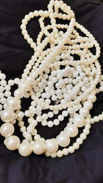 黑色背景上的珍珠女性珠宝。背景设计，摄影新颖。纺织品，面料模板，现代照片。图片下载