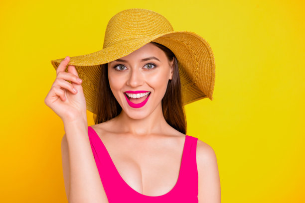 特写照片，快乐、酷炫、兴奋、惊讶的美丽女孩，化着时尚妆容，触摸着时髦宽边帽，朝着镜头大笑，背景色彩鲜艳。图片下载