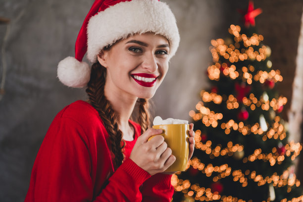 年轻女孩在公寓室内穿着毛衣，手握咖啡杯，剪裁的侧面照片，充满圣诞节的节日气氛。图片下载