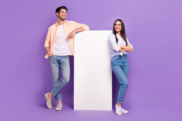 两个人展示空白巨大智能手机触摸屏的全身照片，背景为紫色。图片下载