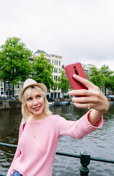 年轻女性在阿姆斯特丹用手机自拍的竖拍照片图片下载