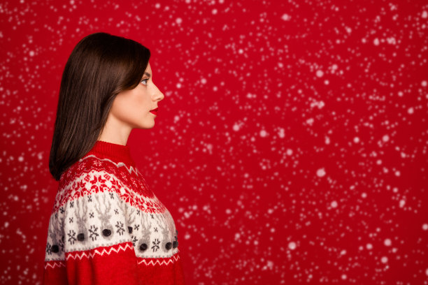 侧面照片，展现了一位可爱、心情愉悦的女性，短发，穿着红色毛衣，面向空旷的空间，背景为红色。图片下载