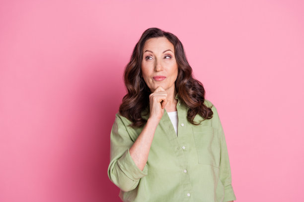 成功的销售经理或市场专员的肖像照片，年长女性托着下巴思考，背景为粉色。图片下载