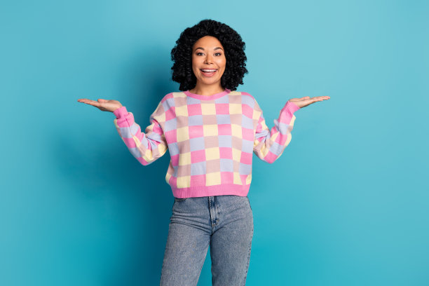 可爱的年轻女士在蓝色背景下穿着时尚的粉色格子服装，手持空白空间的照片肖像。图片下载