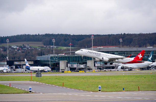 侧面视角的乘客飞机，Helvetic Airways的Embraer E195AR，注册号HB-JVW，正在云雾缭绕的秋日下午从苏黎世机场起飞。照片拍摄于2024年12月8日，瑞士苏黎世克洛滕。图片下载