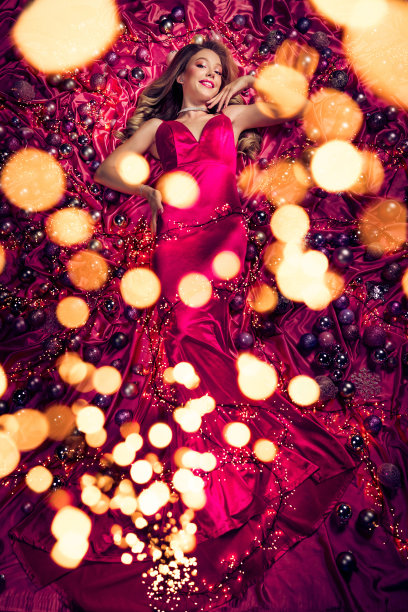 圣诞魔法女士躺在粉色织物上，周围环绕着灯饰、树木和玩具的顶级照片图片下载