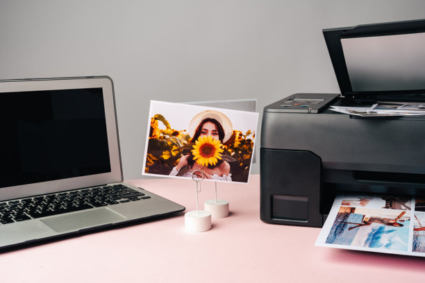 桌子上的电脑笔记本和打印机。正在打印照片。图片下载