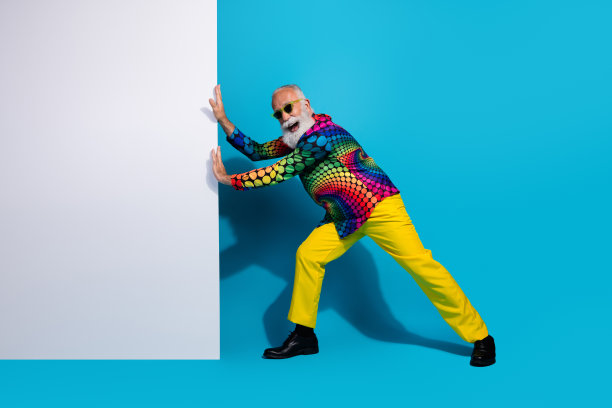 时尚迷人的老年男子在蓝色背景上推动空白广告牌的全身照片图片下载