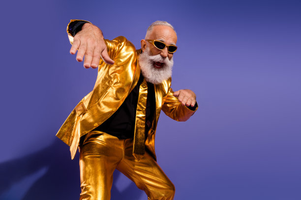 兴奋的胡须绅士在紫色背景下穿着时尚的金色衣服，调皮地跳舞的照片肖像图片下载