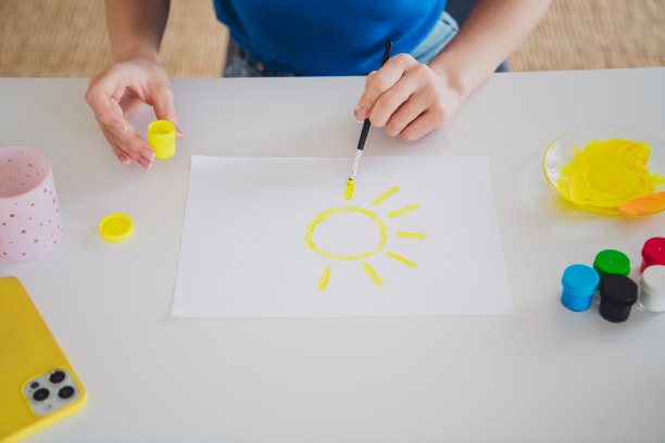 剪裁照片，金发少女在家居室内的温馨环境中穿着蓝色服装，享受绘画阳光的爱好。图片下载