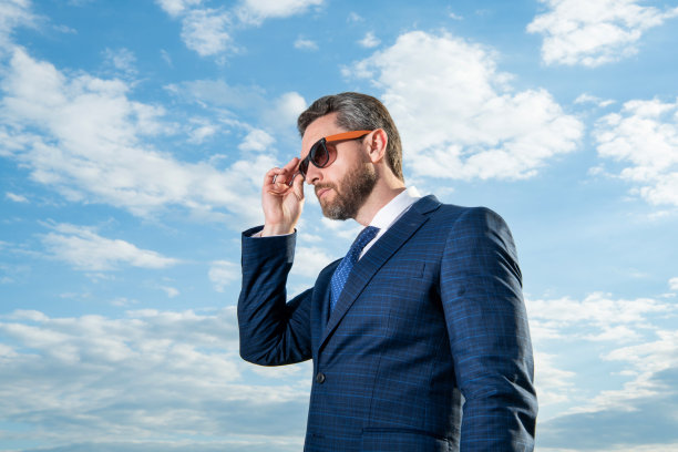 身穿商务西装的首席执行官照片。身穿西装的首席执行官在天空背景下。身穿西装的首席执行官在户外。图片下载