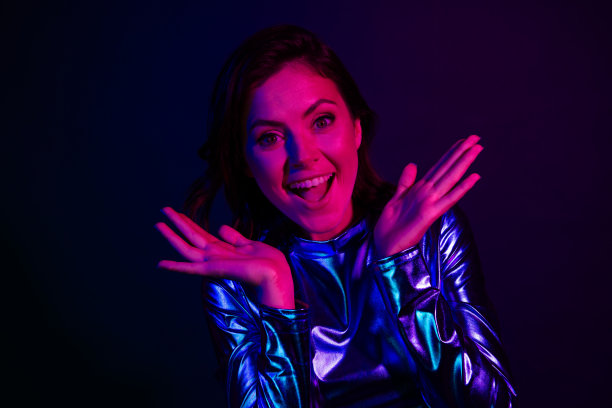 穿着时尚迪斯科复古服装的漂亮年轻女孩在黑色背景下兴奋地做出搞笑反应的照片肖像图片下载