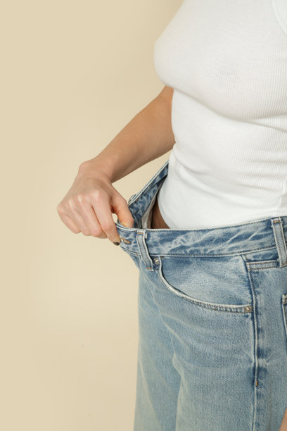 年轻的高加索女性在减肥后穿着宽松牛仔裤的工作室照片图片下载