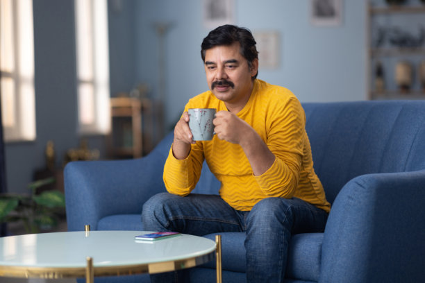 印度男子在家沙发上喝咖啡的库存照片图片下载