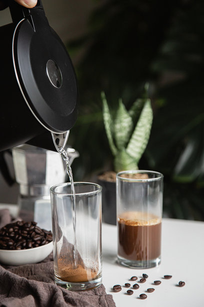 手持水壶将热水倒入咖啡杯。家中自制咖啡，竖版照片图片下载