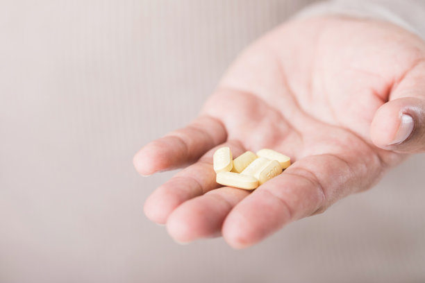 一名男子手中握着几颗黄色药丸，突显了超出处方限制的过量风险。这张图片强调了遵循医疗建议以安全用药的重要性。图片下载