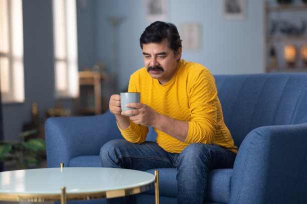 印度男子在家沙发上喝咖啡的库存照片图片下载