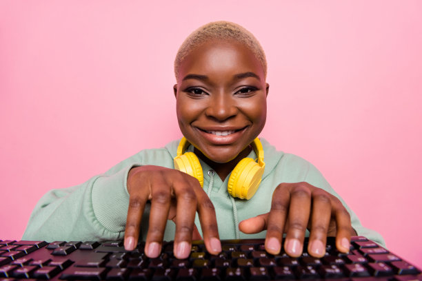 漂亮女孩自由职业者程序员在粉色背景上编写新软件程序的照片图片下载