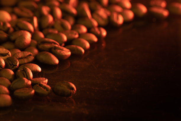 咖啡豆照片，背景为棕色，留有空白空间。深烘焙的棕色咖啡豆堆叠在一起，展现独特的纹理。图片下载
