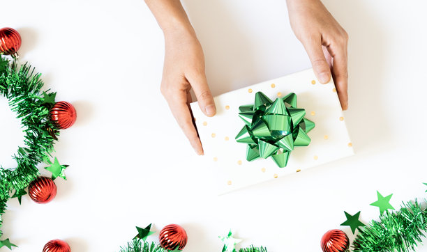 圣诞前夕概念。俯视照片中有礼品盒、缎带蝴蝶结、绿色和红色的球饰、金色星星装饰物以及松枝，背景为孤立的红色，中央留有空白空间。图片下载