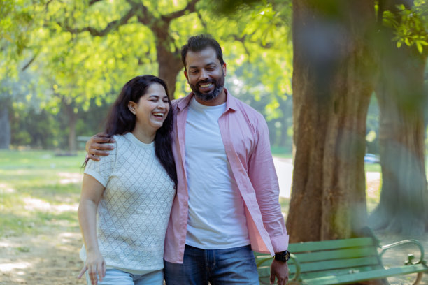 快乐的散步：一对情侣享受宁静的时刻，一张抓拍的照片，展示了一对幸福的情侣手挽手走过郁郁葱葱的公园。图片下载