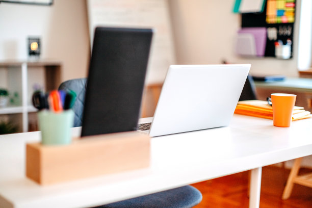 现代办公室的照片，桌上放着打开的笔记本电脑，几个人正在休息。图片下载