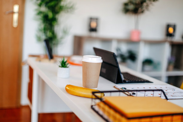 现代办公室桌子的照片，没有人，只有一杯咖啡和一根香蕉。图片下载