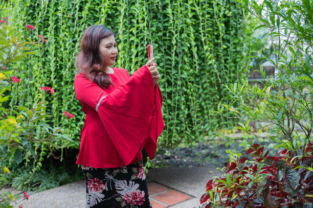 亚洲女性在户外花园中走动并使用智能手机的库存照片图片下载