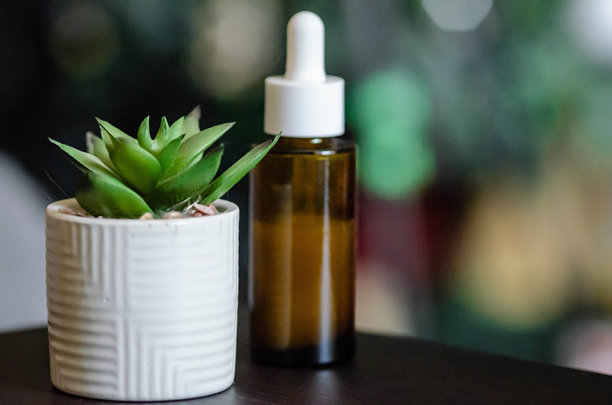 美容概念，黑色木桌上摆放着精华液瓶和芦荟植物的静物照片图片下载