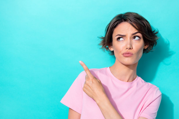 特写照片，漂亮可爱的女士好奇地看着，手臂指向空旷的空间，考虑决策，背景为青色。图片下载