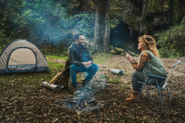 妻子在帐篷前拍摄丈夫享受时光的照片图片下载