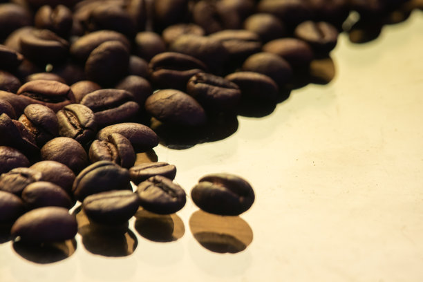 咖啡豆照片，背景为黄色，留有空白。深色烘焙的棕色咖啡豆，独特的纹理堆放在一起。图片下载