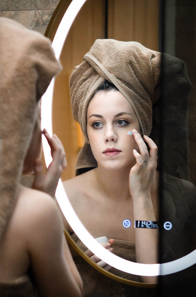 年轻女性在脸上涂抹保湿护肤品 - 股票照片图片下载