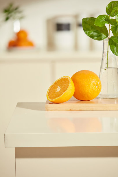 空白的厨房台面用于厨房产品广告照片设计，装饰着一些新鲜的橙色和绿色植物。前景特写，模糊的厨房背景。图片下载