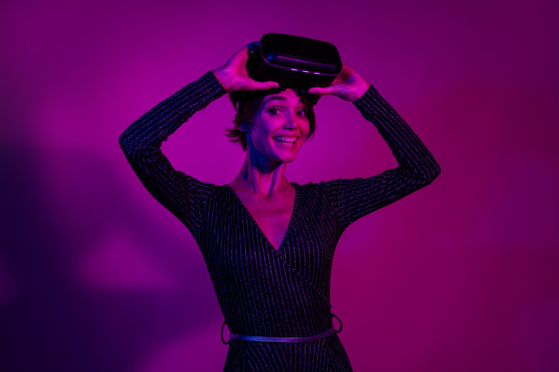 可爱的年轻女士在霓虹粉色背景下脱下耳机，穿着时尚的工装服进行照片肖像拍摄。图片下载