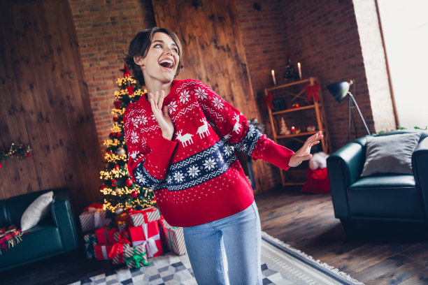 年轻的模特圣诞老人的照片助手舞者穿红色毛衣牛仔牛仔裤快乐新年前夕dj孤立室内工作室背景图片下载