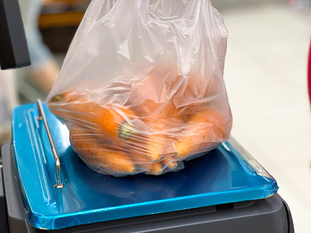 超市收银台上称重的新鲜胡萝卜装在塑料袋里图片下载