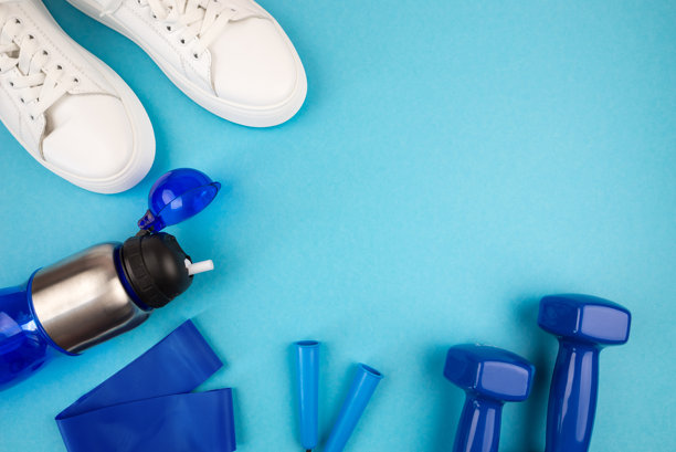 运动配件的概念。白色运动鞋、蓝色哑铃、蓝色瑜伽垫及其他运动器材的照片。图片下载