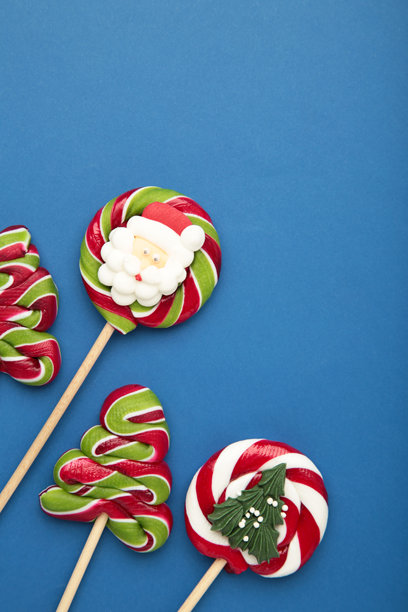 蓝色背景上的圣诞糖果。甜美的棒棒糖。竖版照片图片下载