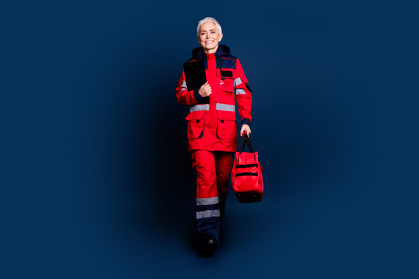穿着红色制服的可爱退休女士在深蓝色背景下提供紧急医疗帮助的全身照片图片下载